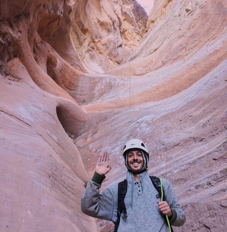 Alec standing in a sandstone canyon wearing a climbing helmet
